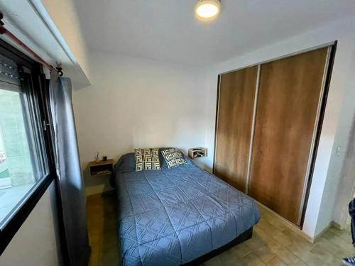 Habitación pequeña con cama y armario de madera. en San Juan Primero en San Bernardo
