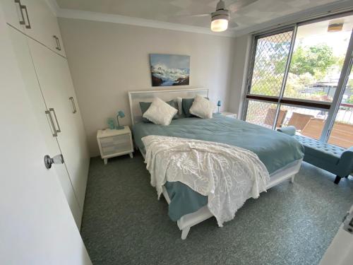 a bedroom with a bed and a large window at Aqua on Bribie 100 metres to Beach and Shops in Bongaree