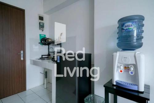 ein rotes Wohnzimmer mit einem roten Living-Logo und einer Maschine in der Unterkunft RedLiving Apartemen Gunung Putri Square - Sansan Room in Parungtandjung