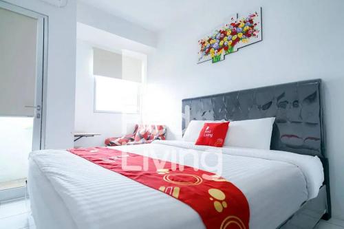 um quarto com uma cama grande e um cobertor vermelho em RedLiving Apartemen Gunung Putri Square - Sansan Room with Netlfix em Parungtandjung