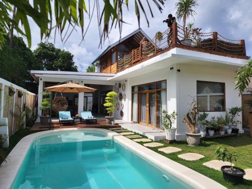 a villa with a swimming pool in front of a house at Rumah Tara Gili Air Rooftop Bungalow with Terrace and Whirlpool in Gili Air