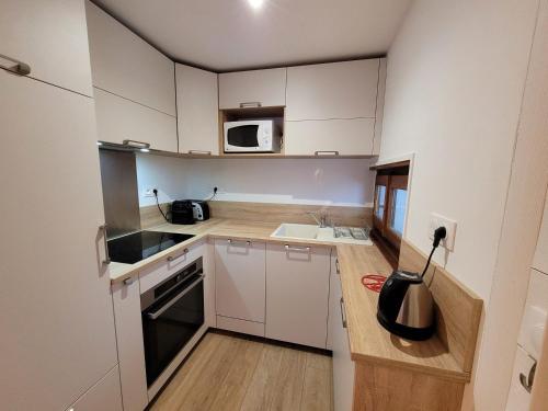 une petite cuisine avec des armoires blanches et un micro-ondes dans l'établissement Bel appartement rénové 2 pièces avec balcons, proche du centre, parking, Wi-Fi - FR-1-598-119, aux Gets