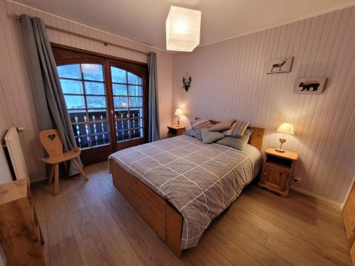 une chambre avec un lit et une grande fenêtre dans l'établissement Bel appartement rénové 2 pièces avec balcons, proche du centre, parking, Wi-Fi - FR-1-598-119, aux Gets