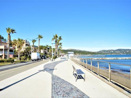un banc sur un trottoir à côté de la plage dans l'établissement Studio cosy avec jardin, proche plage à Cavalaire-sur-Mer, parking inclus - FR-1-226B-128, à Cavalaire-sur-Mer