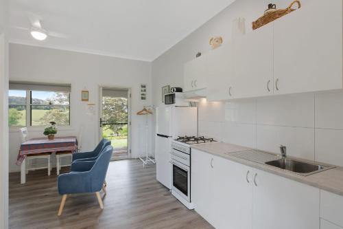 a white kitchen with a sink and a table at Henkley Cottage 2 Jeremiah in Central Tilba