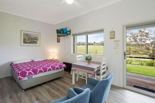 a bedroom with a bed and a table and chairs at Henkley Cottage 2 Jeremiah in Central Tilba