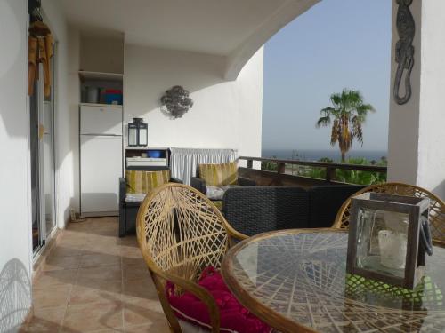 サンミゲル・デ・アボナにあるOne Bed Apartment Free WiFi Stunning views to sea, marina and mountainsのリビングルーム(ガラスのテーブル、椅子付)