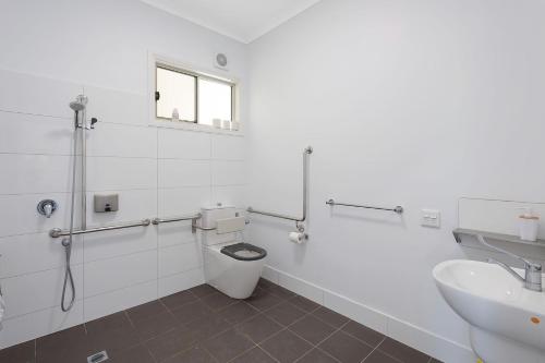 a white bathroom with a toilet and a sink at Henkley Cottage 3 Ezekiel in Central Tilba