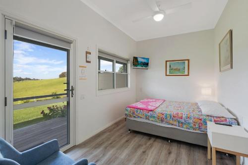 a bedroom with a bed and a sliding glass door at Henkley Cottage 3 Ezekiel in Central Tilba