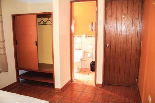 a bathroom with a toilet and a wooden door at T'ika Guest House in Cusco