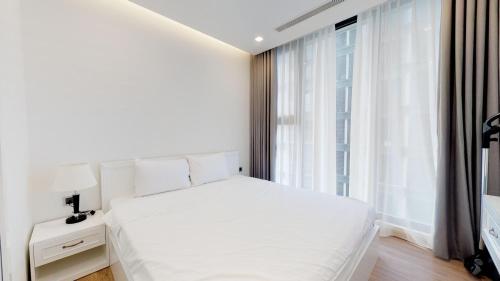 a white bedroom with a white bed and a window at vinhomes metropolis 3 phòng ngủ in Hanoi