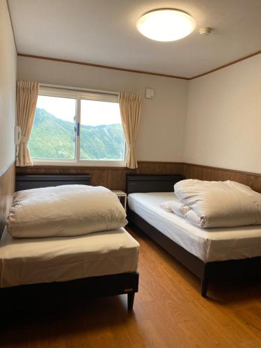 two beds in a room with a window at Tengudaira Mountain Lodge in Tateyama