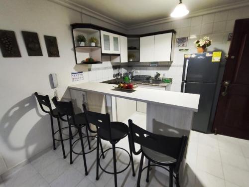 a kitchen with a counter with chairs and a refrigerator at Condominio Nuevo Rodadero, wifi piscina parqueadero in Santa Marta