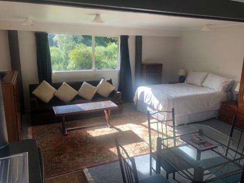 a bedroom with a bed and a couch and a window at Spiral Gardens Country Park Retreat in Raurimu Spiral