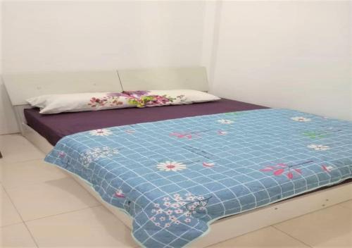 - un lit avec une couette bleue et des fleurs dans l'établissement Samarahan Homestay 3-bedrooms house, à Kuching