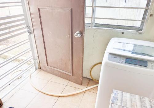 a laundry room with a door and a washing machine at Samarahan Homestay 3-bedrooms house in Kuching