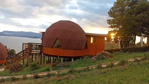 una pequeña casa con techo en la cima de una colina en Domos lago Muisca Xue, en Aquitania