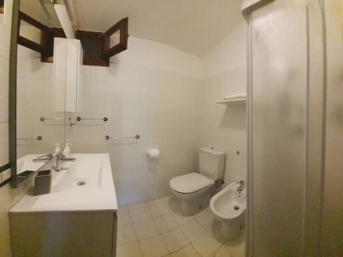 a white bathroom with a toilet and a sink at Villa Capodorso, Palau Porto Pollo in Palau