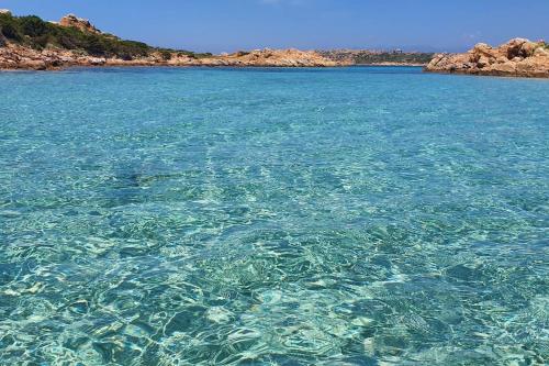 a large body of clear blue water next to a beach at Villa Capodorso, Palau Porto Pollo in Palau