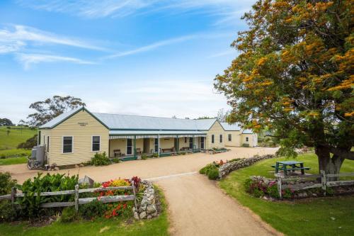 a large yellow building with a bench in front of it at Henkley Cottage 3 Ezekiel in Central Tilba