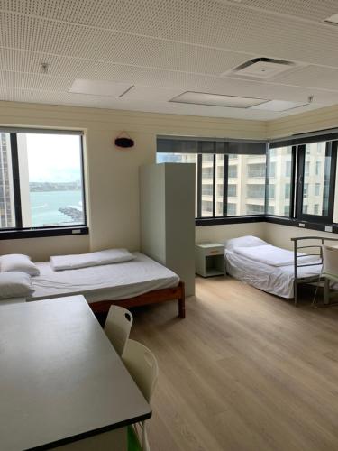 2 camas en una habitación con ventanas grandes en Garden Hostel en Auckland