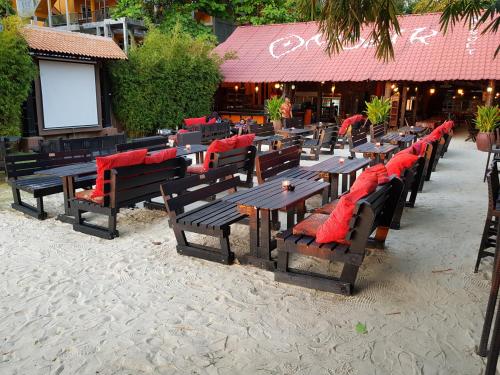 a row of wooden tables and chairs with red pillows at Ombak Dive Resort Perhentian Island in Perhentian Island