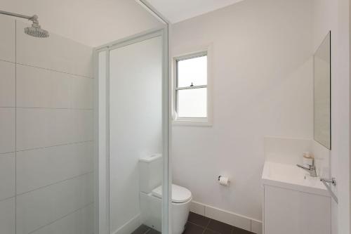 a white bathroom with a toilet and a window at Henkley Cottage 4 Daniel in Central Tilba