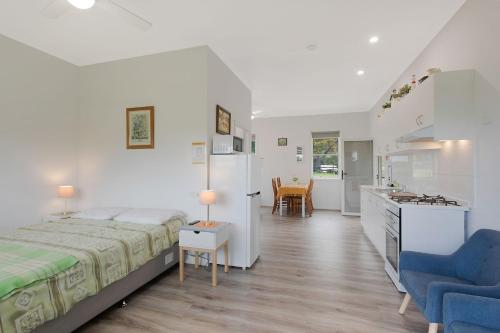 a white bedroom with a bed and a kitchen at Henkley Cottage 4 Daniel in Central Tilba