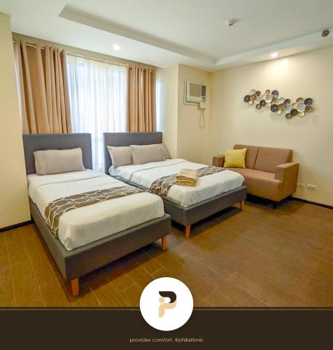 une chambre d'hôtel avec deux lits et un canapé dans l'établissement SPACIOUS 2BR NEAR MOA, SOLAIRE CASINO AND PASAY AREA, à Manille
