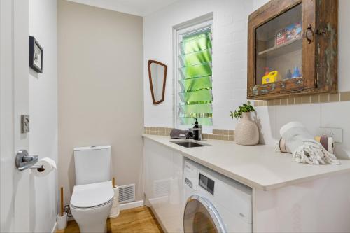 a bathroom with a sink and a washing machine at Little cove gem - walking distance to the most famous Noosa beach! in Noosa Heads