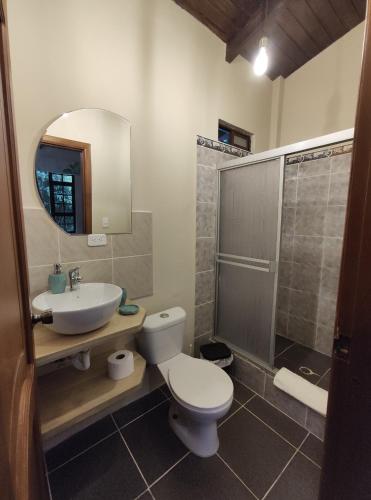 y baño con aseo, lavabo y ducha. en "Casa Verde" en Baños de Agua Santa con vista al volcán Tungurahua, en Baños