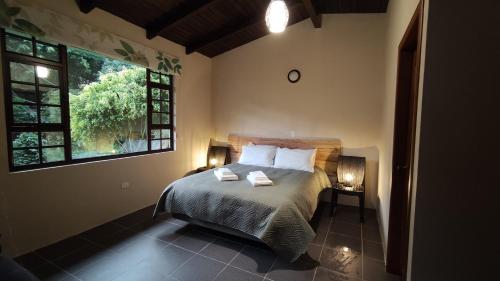 una camera da letto con un letto con due cuscini e una finestra di "Casa Verde" en Baños de Agua Santa con vista al volcán Tungurahua a Baños