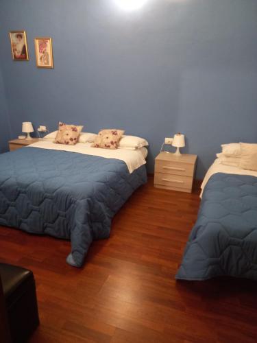two beds in a room with blue walls and wooden floors at with FREE secure PARKING GARAGE - The CityCentre Junior Suite- All comforts - zone Arco della Pace - Castello Sforzesco -Last supper -nearest metro subway greenline M2 Moscova in Milan