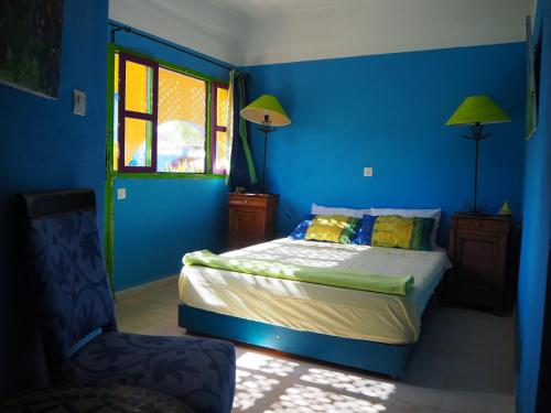 een blauwe slaapkamer met een bed en een raam bij La Kasbah du Paradis in Aksri