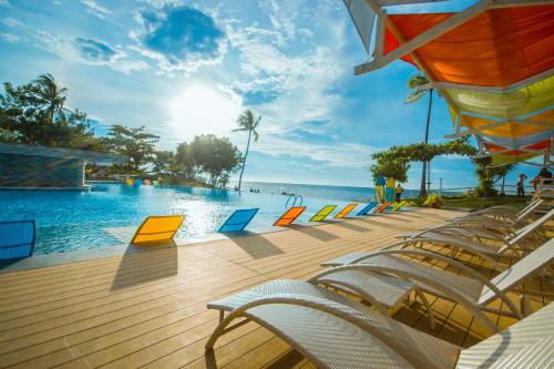 a swimming pool with chairs and the ocean at Maayo San Remigio in San Remigio