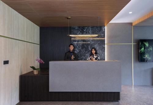 un hombre y una mujer parados en un mostrador en un vestíbulo en Forest Hills Hotel en Soreang