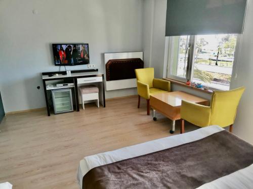 a bedroom with a desk and a table and yellow chairs at Hotel Simsek in Finike