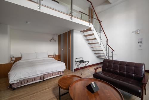 ein Schlafzimmer mit einem Bett und einem Sofa und einer Treppe in der Unterkunft Anping Kensington Hotel in Anping