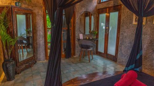 a living room with a bed and a table and windows at Firefly Eco Lodge in Ubud