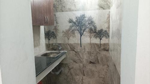 La salle de bains est pourvue d'un lavabo et d'arbres sur le mur. dans l'établissement Tru Comfort, à Pondichéry