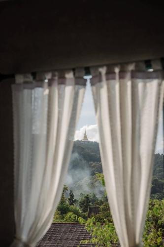 a window with curtains with a view of a mountain at โรงแรมมีวาสนา - Me Vadsana Hotel in Ban Thung Yao