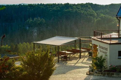 a building with a roof with tables and chairs at Hotel Zur Aussicht in Hohnstein