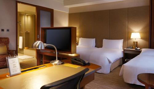 a hotel room with two beds and a television at San Want Residences Taipei in Taipei