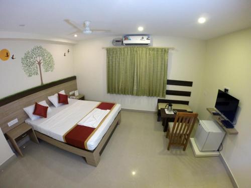 een slaapkamer met een bed, een bureau en een televisie bij HOTEL GREEN TREES in Bangalore