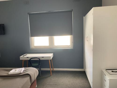 a room with a desk and a window with a window shade at Union Club Hotel in Colac