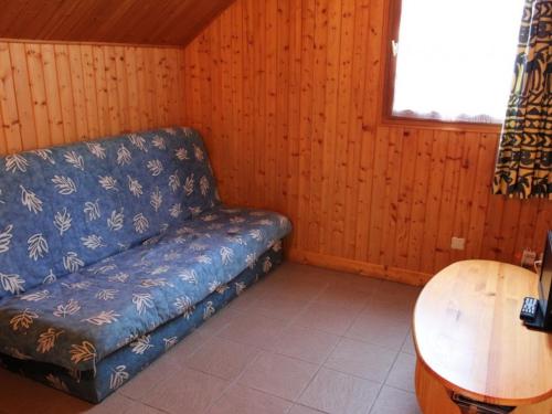 ein Wohnzimmer mit einem blauen Sofa und einem Tisch in der Unterkunft Gîte Mesples, 3 pièces, 4 personnes - FR-1-489-402 in Mesples