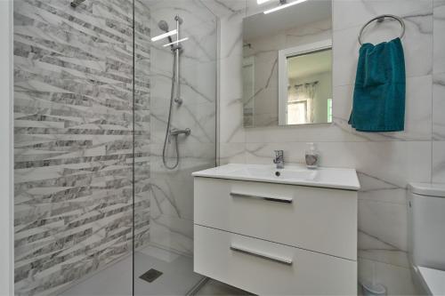 La salle de bains blanche est pourvue d'un lavabo et d'une douche. dans l'établissement Verano Azul, à Nerja