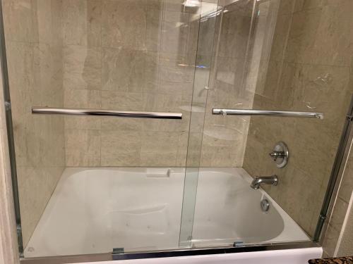 a shower with a glass door next to a tub at LuxHome Suites in Mansion in Riverside