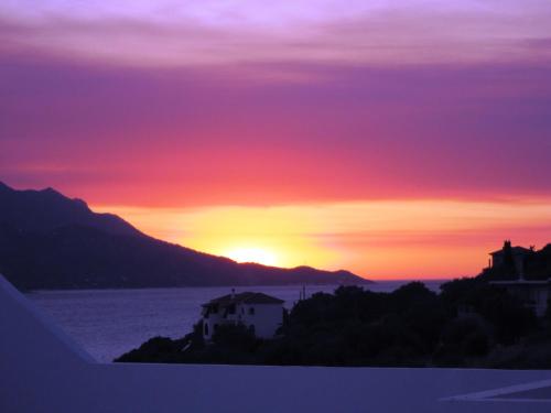 a sunset over a body of water with a house at Scorpios Hotel & Suites in Samos