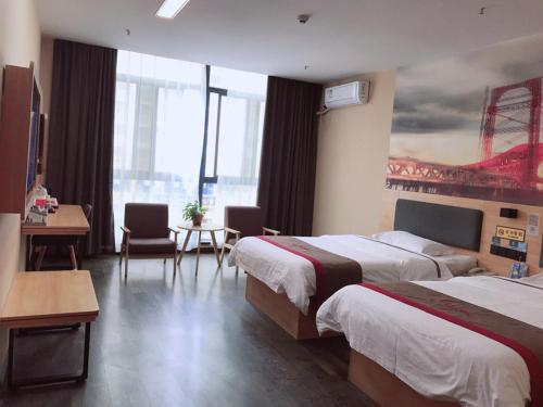 a hotel room with two beds and a desk at Thank Inn Chain Hotel henan zhengzhou xinzheng city north china road xuanyuan lake in Zhengzhou